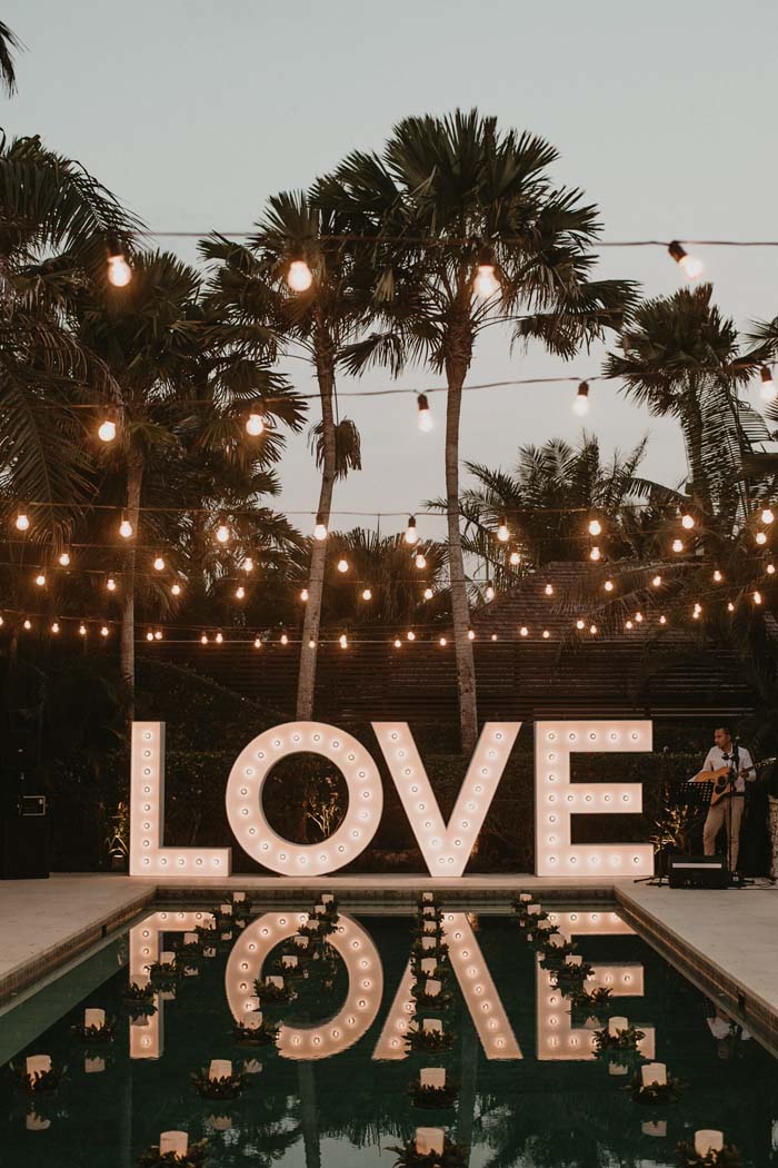 wedding by the pool and lit up LOVE sign 